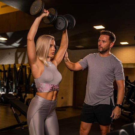 Five Jumeirah Village Dubai Esterno foto Personal trainer assisting a woman with a dumbbell press