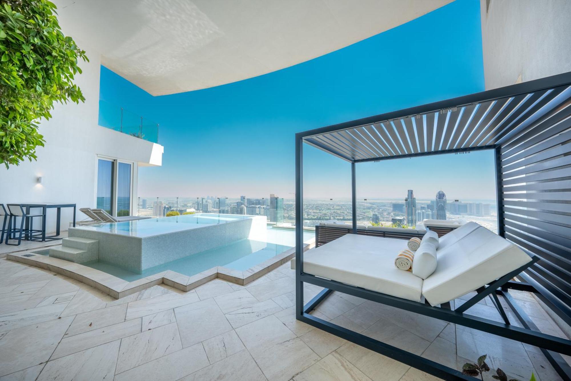 Five Jumeirah Village Dubai Esterno foto The photo shows a luxurious outdoor space that features a modern infinity pool and a stylish lounging area. The pool appears to be surrounded by sleek stone tiles, creating a beautiful contrast with the bright blue sky above. There is a contemporary 
