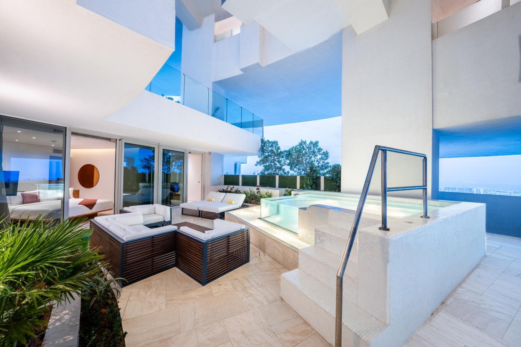 Five Jumeirah Village Dubai Esterno foto The photo shows a modern and stylish outdoor area that appears to be part of a contemporary residence. It features a seating arrangement with a lounge set made of dark wood and cushions, providing a comfortable space for relaxation. Nearby, there is 